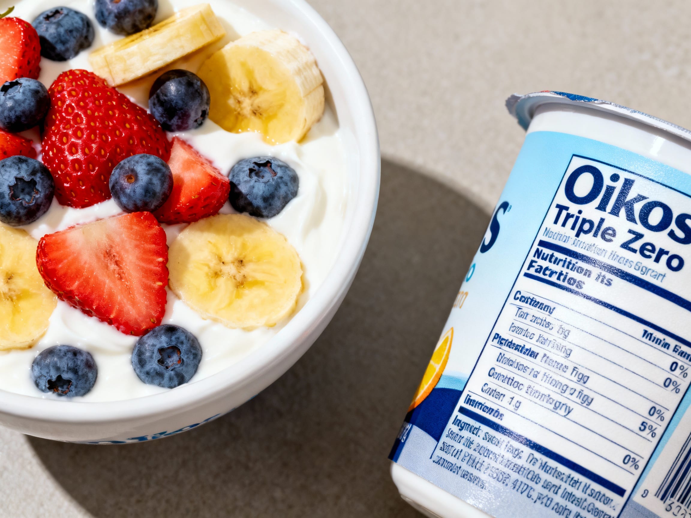 a bowl of Oikos Triple Zero yogurt with fruit, next to a zoomed-in nutrition label