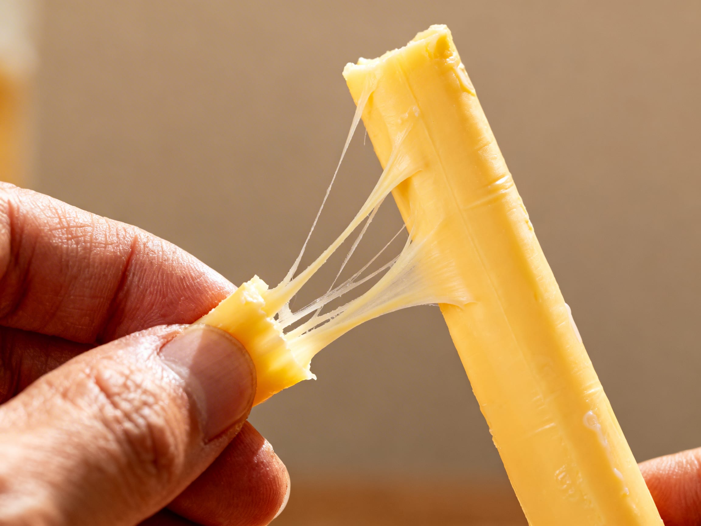 a hand peeling a string cheese stick